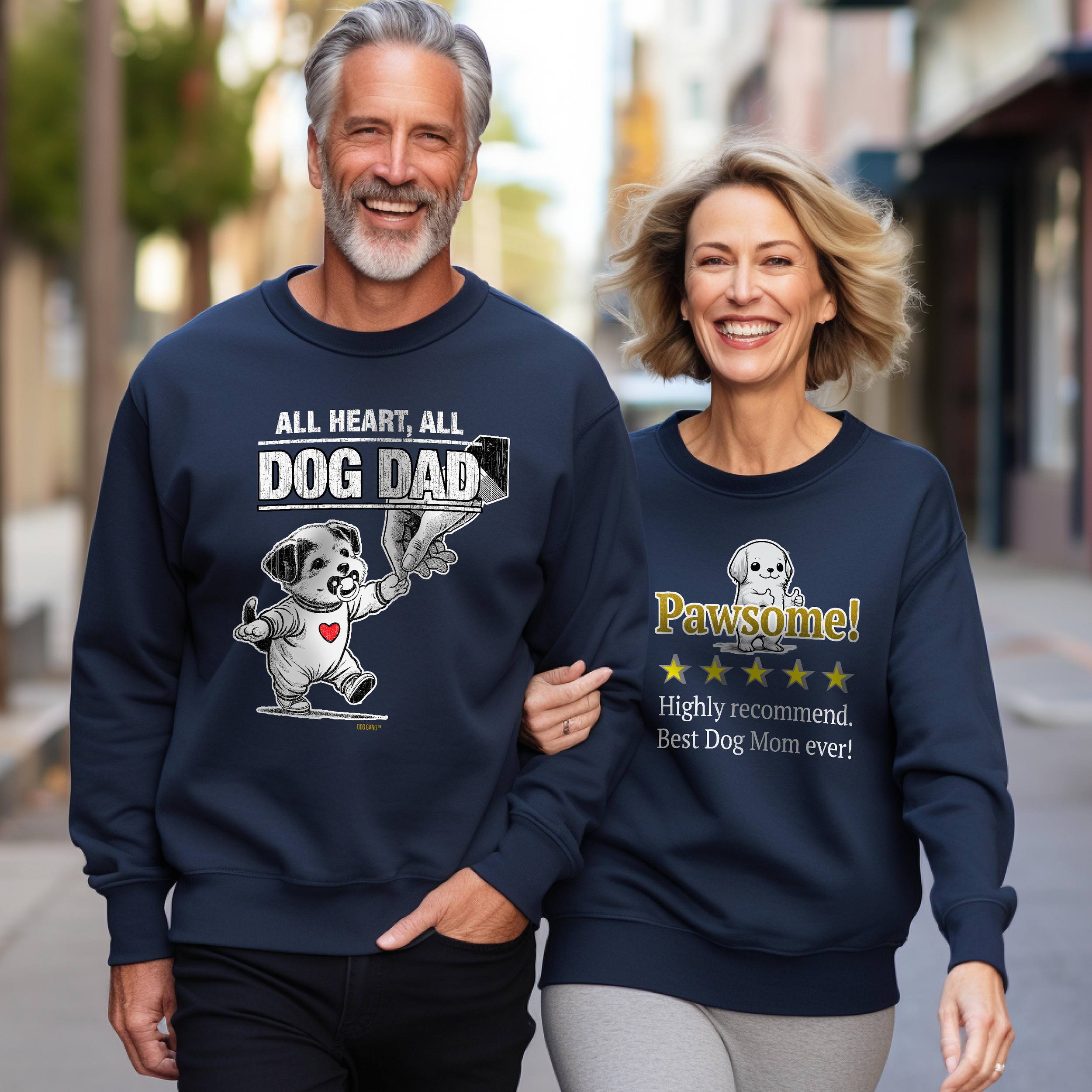 A man and woman are walking side by side, smiling on a city street. The man wears a sweatshirt with All Heart, All Dog Dad and a dog graphic. The woman wears a sweatshirt saying Pawsome! Highly recommend. Best Dog Mom ever! with a dog image.