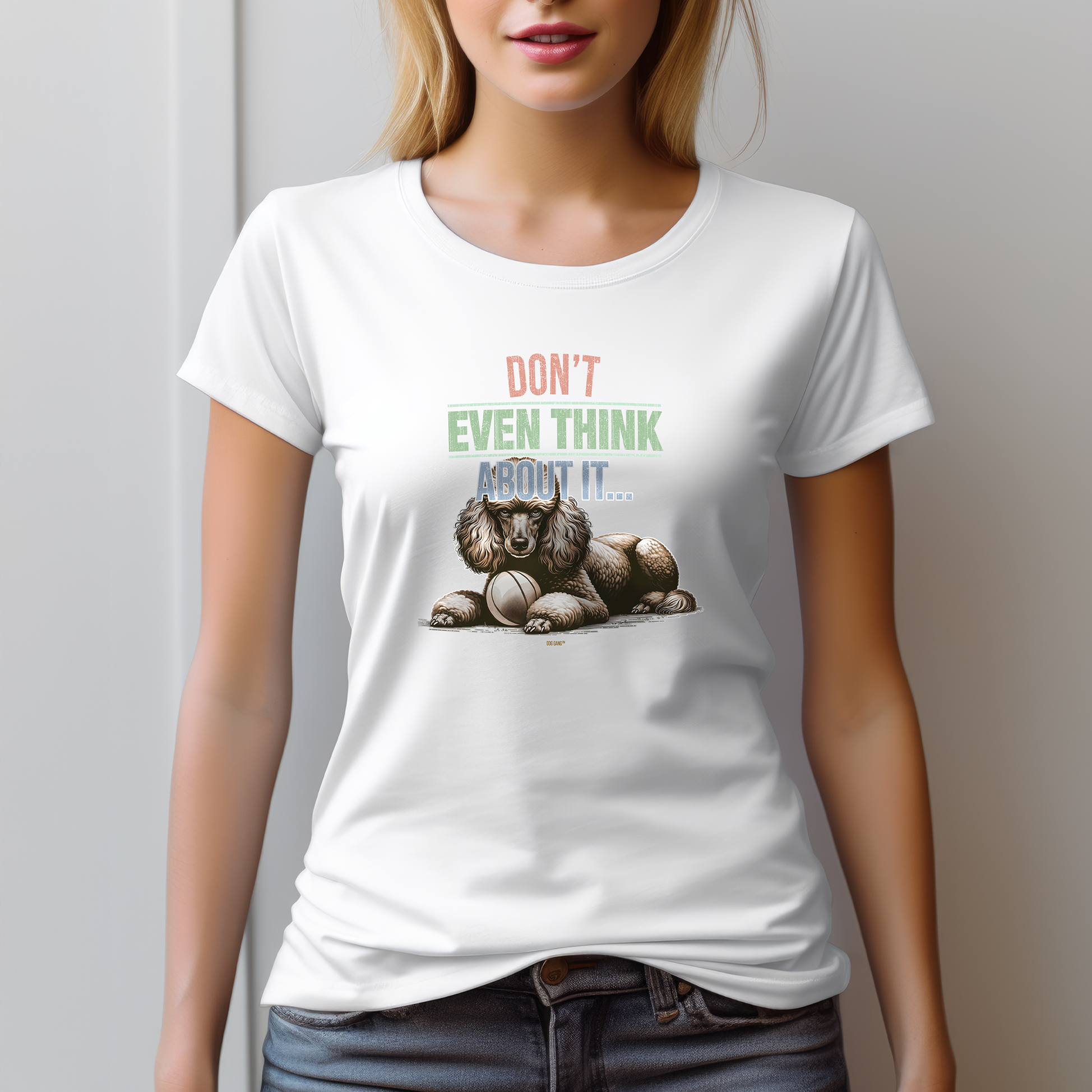 A woman wearing a white T-shirt with a dog illustration and the text Dont even think about it... printed on it. She is standing against a light-colored wall with her hands by her sides.